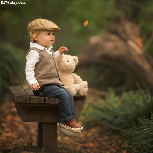 a little boy sitting on a bench with a teddy bear