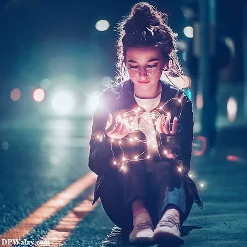 a little girl sitting on the ground holding sparkles