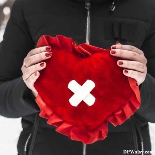a woman holding a red heart with a cross on it dp breakup 