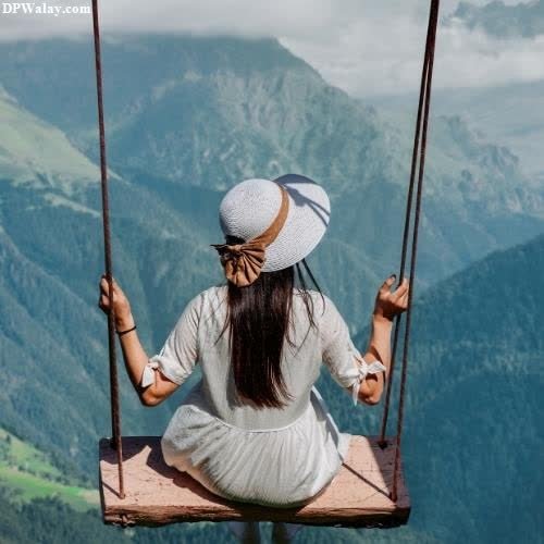 a woman sitting on a swing in the mountains 