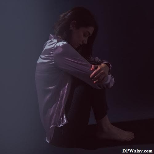 sad girl dp - a woman sitting on the floor in the dark