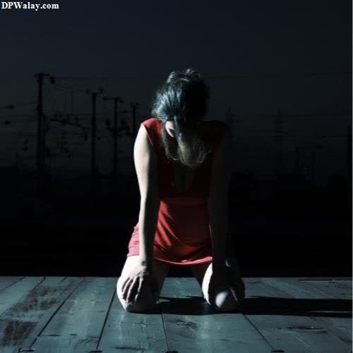 sad girl dp - a woman sitting on a wooden floor in the dark