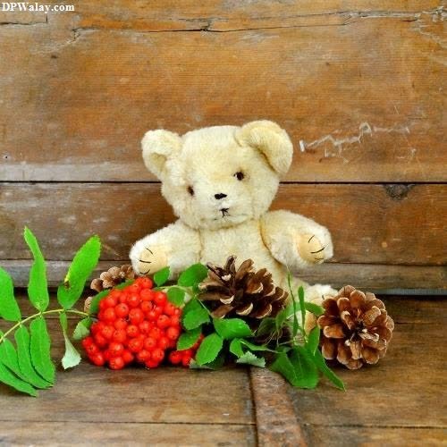 a teddy bear sitting on a wooden bench with berries and pine cones