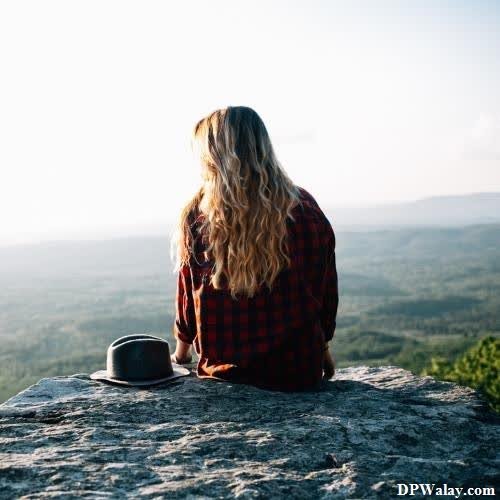 a woman sitting on top of a rock looking out over the mountains