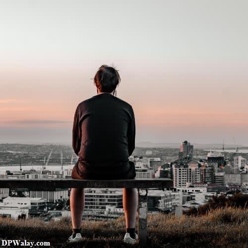 a man sitting on a bench looking out over a city