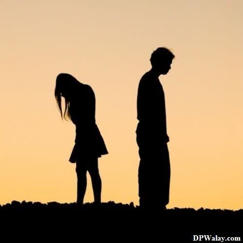 a couple standing on top of a hill at sunset