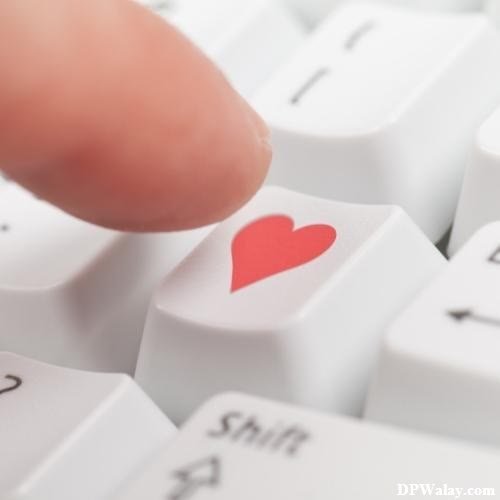 a person's finger pressing a red heart on a computer keyboard