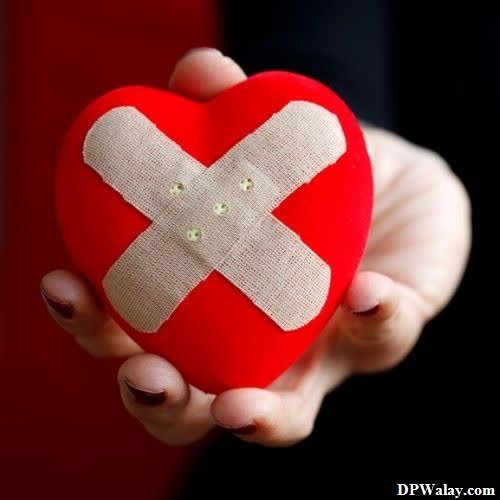 i hate love dp - a person holding a red heart with a bandage on it