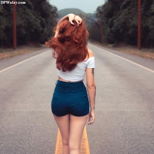 a woman walking down the road with her hair in the air