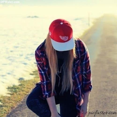 a girl in a red hat and plaid shirt sitting on a road