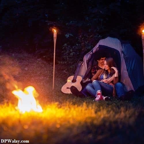 a couple sitting in front of a campfire