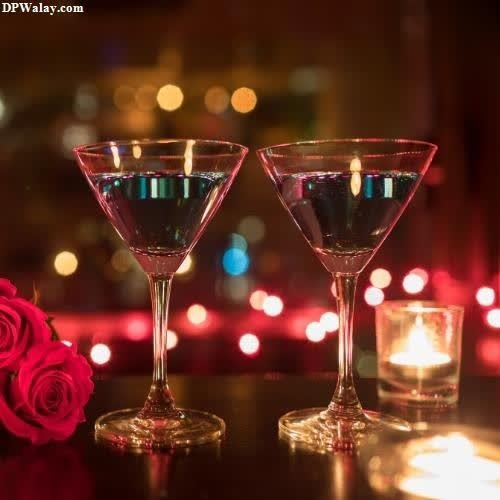 two glasses of wine and roses on a table images by DPwalay