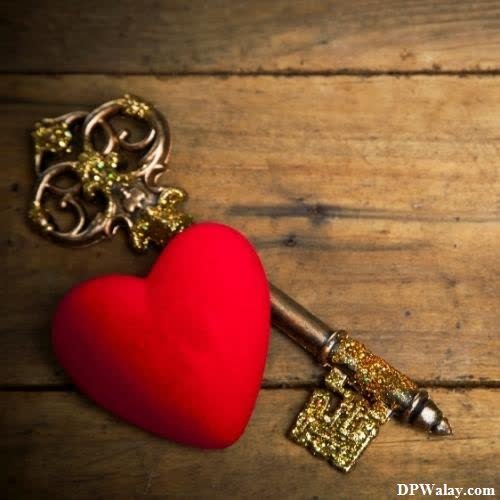 a red heart with a key on a wooden table