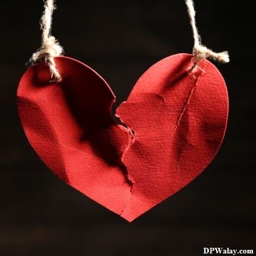 breakup dp - a heart hanging from a string on a black background