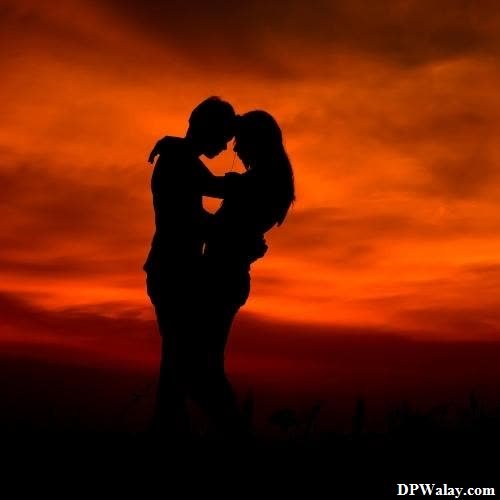 a silhouette of a couple kissing in front of a sunset