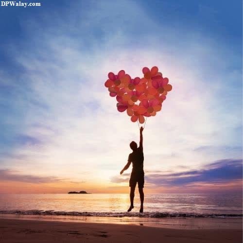 a person holding up balloons on the beach 