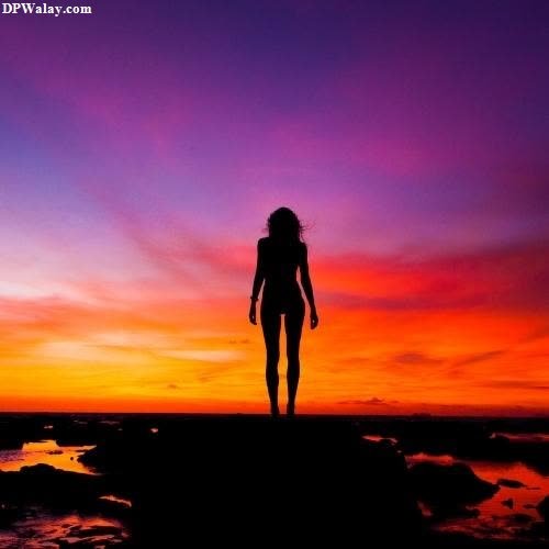 a woman standing on a rock at sunset images by DPwalay