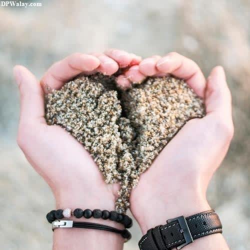 two hands holding sand hearts