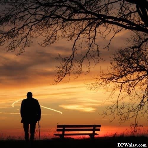a man standing in front of a bench at sunset