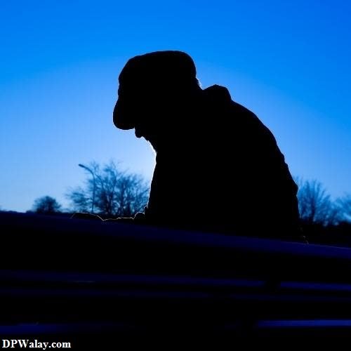 a silhouette of a man sitting on a bench images by DPwalay