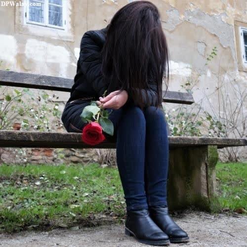a woman sitting on a bench with a rose