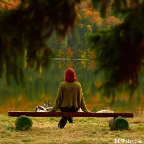 a woman sitting on a bench in front of a lake 