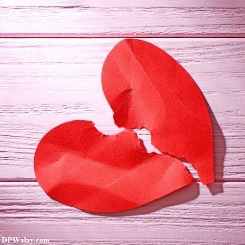 a red heart cut in half on a white wooden background