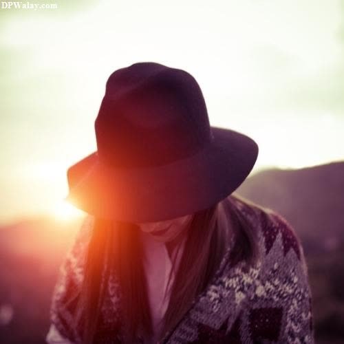 a woman in a hat and sweater looking at the sun sad female dp