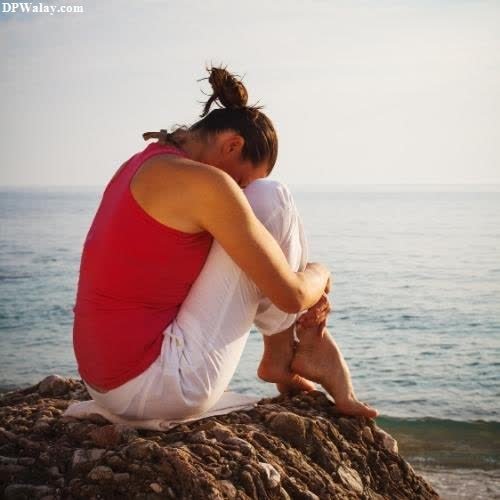 a woman sitting on a rock looking out at the ocean-YKc6