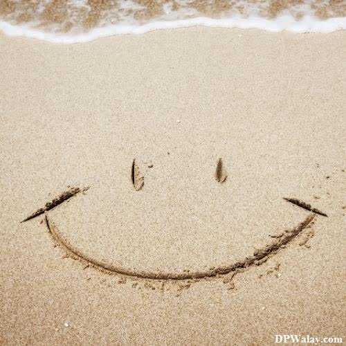 a smiley face drawn in the sand on a beach-HTQO