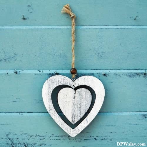 a heart hanging on a blue wooden wall 
