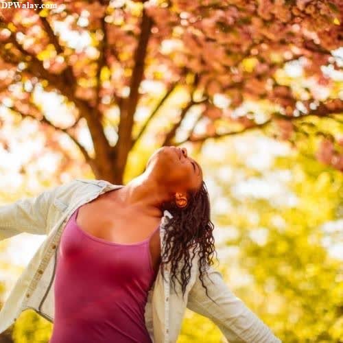 unique dp for whatsapp - a woman in a pink shirt and white jacket is standing in front of a tree