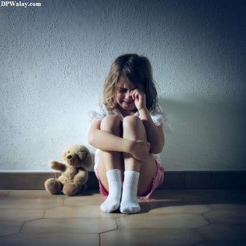a little girl sitting on the floor with her teddy bear
