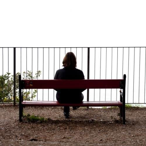 a woman sitting on a bench looking out over the water