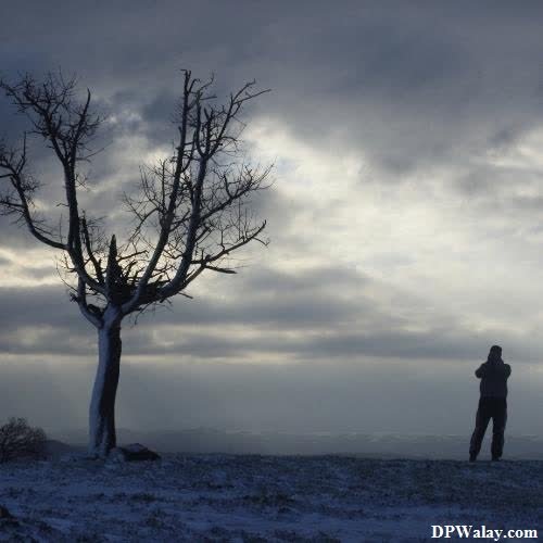 a man standing in the snow with a tree in the background