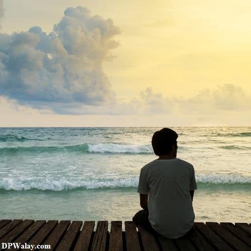 a man sitting on a wooden pier looking out at the ocean very sad whatsapp dp 