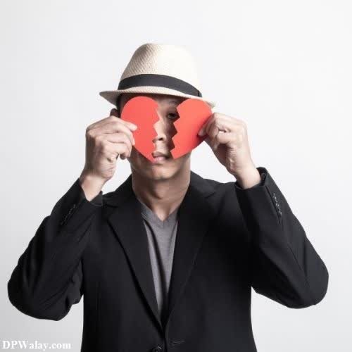 a man in a hat holding a red heart