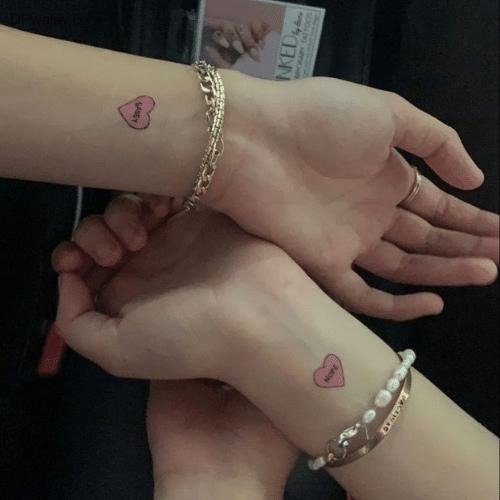 two people holding hands with tattoos on their wrists