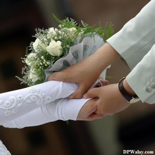 a couple holding hands with flowers on their wedding day