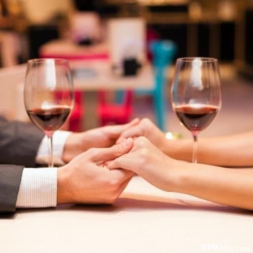 a couple holding hands while sitting at a table