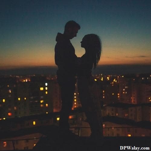 a couple kissing on the roof of a building at night