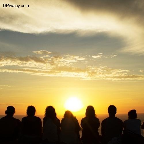 a group of people sitting on top of a mountain watching the sunset