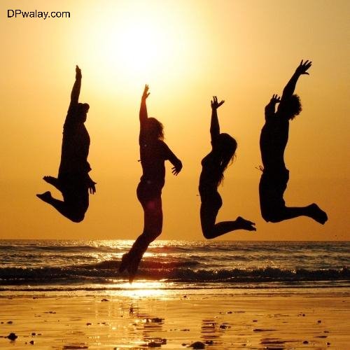 three people jumping on the beach at sunset