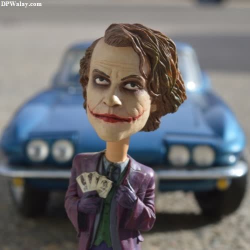 a toy of the joker with a car in the background