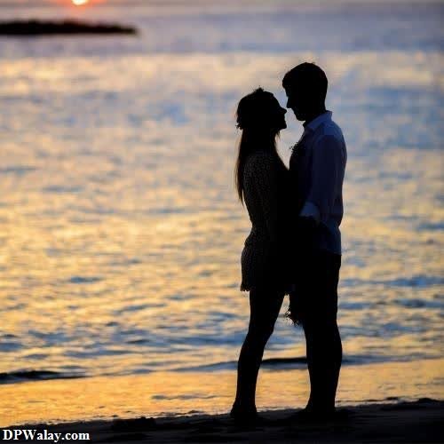 a couple kissing on the beach at sunset