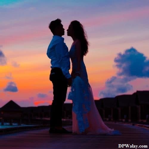 a couple kissing on a dock at sunset 