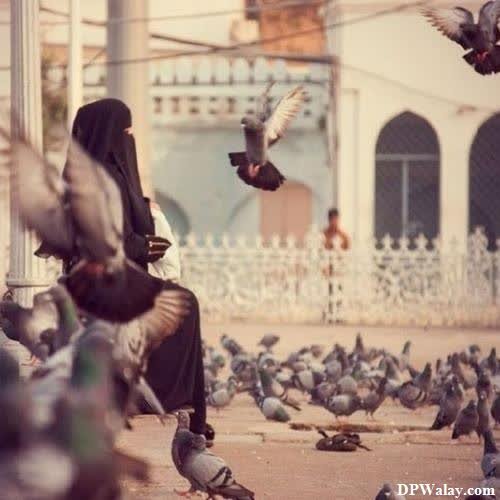 a woman sitting on a bench surrounded by pigeons