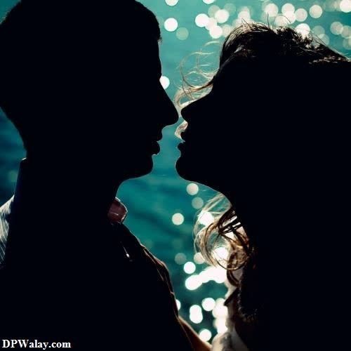 a silhouette of a couple kissing in front of a sparkling background