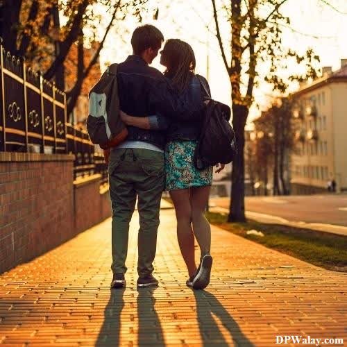 a couple walking down a sidewalk in the sunset