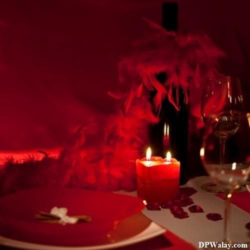 a table set for a romantic dinner with a candle and red wine images by DPwalay